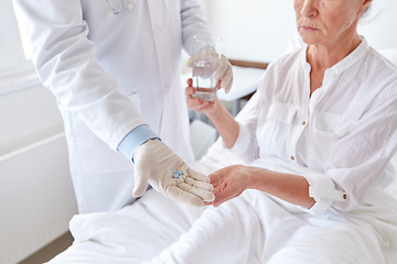 Image showing doctor giving medicine to senior woman at hospital