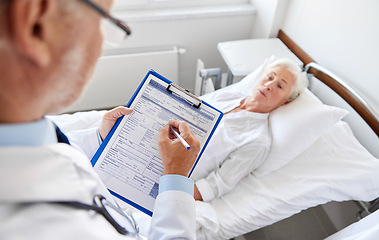 Image showing senior woman and doctor with clipboard at hospital