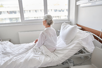 Image showing lonely senior woman sitting in bed at hospital