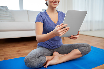 Image showing woman with tablet pc computer doing yoga at home