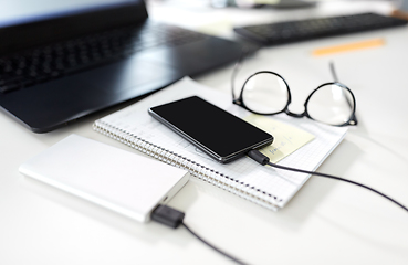 Image showing smartphone with powerbank on table at office