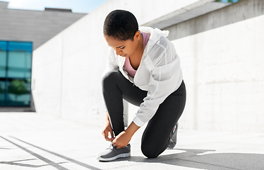 Image showing african american woman tightening sneakers