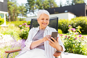 Image showing happy senior woman with phone at summer garden