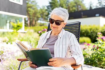 Image showing happy senior woman reading book at summer garden