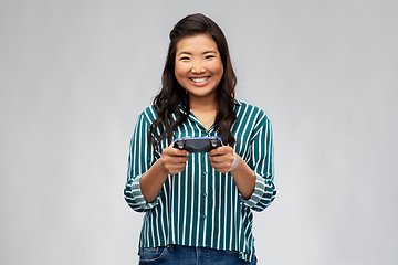 Image showing happy asian woman playing video game with gamepad