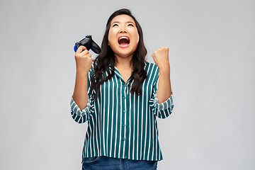 Image showing happy asian woman playing video game with gamepad