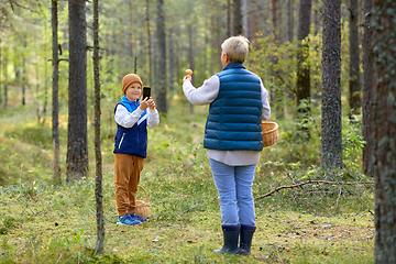 Image showing grandson photographing grandmother with mushroom