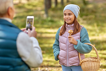 Image showing grandma photographing granddaughter with mushrooms