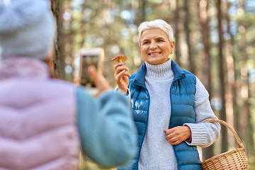 Image showing granddaughter photographing grandma with mushrooms