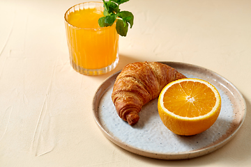 Image showing glass of orange juice and croissant on plate