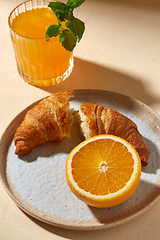 Image showing glass of orange juice and croissant on plate