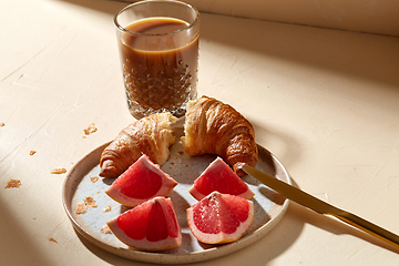 Image showing glass of coffee, croissant and grapefruit on table