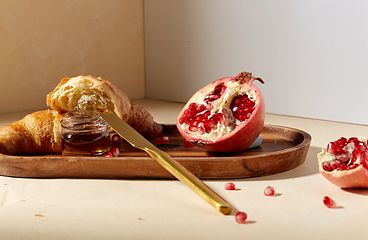 Image showing croissant, pomegranate and honey on wooden tray