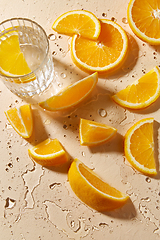 Image showing glass of water and orange slices on wet table