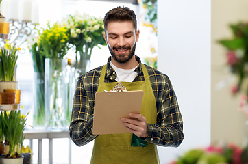 Image showing happy male seller with clipboard at flower shop