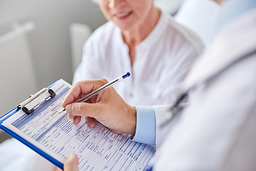 Image showing senior woman and doctor with clipboard at hospital