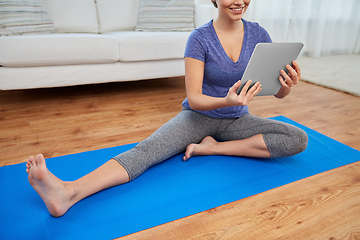 Image showing woman with tablet pc computer doing yoga at home