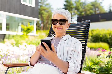 Image showing old woman with earphones and smartphone at garden