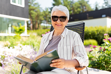 Image showing happy senior woman reading book at summer garden