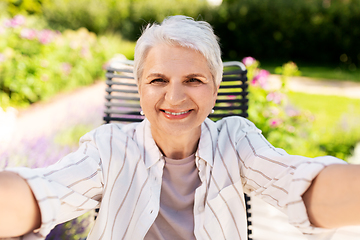 Image showing happy senior woman taking selfie at summer garden