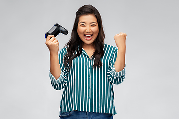 Image showing happy asian woman playing video game with gamepad