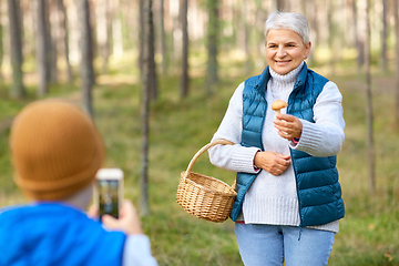 Image showing grandson photographing grandmother with mushroom