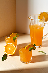 Image showing glasses with orange juice and peppermint on table