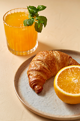 Image showing glass of orange juice and croissant on plate