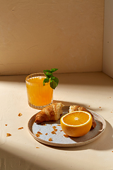 Image showing glass of orange juice and croissant on plate