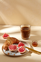 Image showing glass of coffee, croissant and grapefruit on table