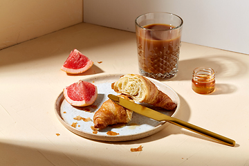 Image showing glass of coffee, croissant and grapefruit on table