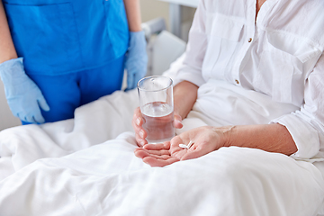 Image showing nurse giving medicine to senior woman at hospital