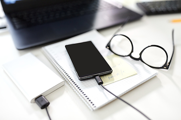 Image showing smartphone with power bank on table at office