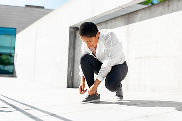 Image showing african american woman tightening sneakers