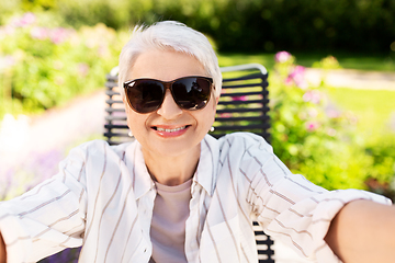 Image showing happy senior woman taking selfie at summer garden