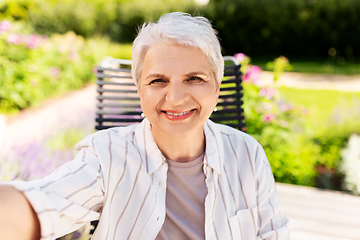 Image showing happy senior woman taking selfie at summer garden