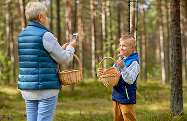 Image showing grandmother photographing grandson with mushrooms