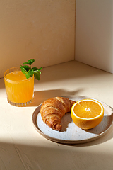 Image showing glass of orange juice and croissant on plate