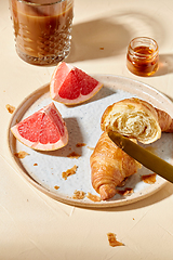 Image showing glass of coffee, croissant and grapefruit on table