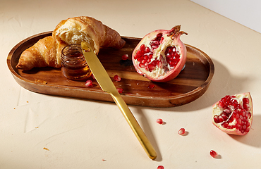 Image showing croissant, pomegranate and honey on wooden tray