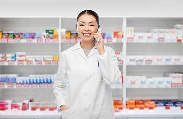 Image showing asian pharmacist calling on phone at pharmacy