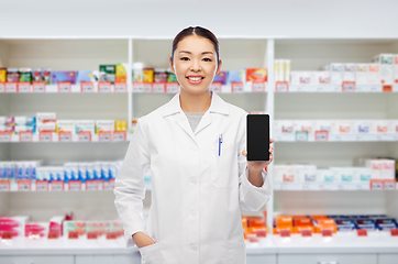 Image showing asian pharmacist with smartphone at pharmacy