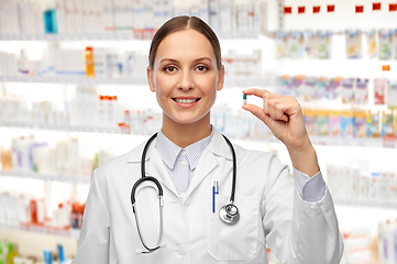 Image showing female doctor holding medicine pill at pharmacy