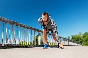 Image showing young man running across city bridge