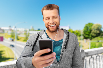 Image showing smiling young man with earphones and smartphone