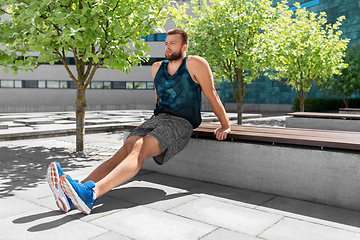 Image showing young man doing triceps dip on city street