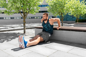 Image showing young man doing triceps dip on city street