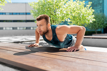 Image showing young man doing push ups on city street