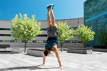 Image showing young man exercising and doing handstand outdoors