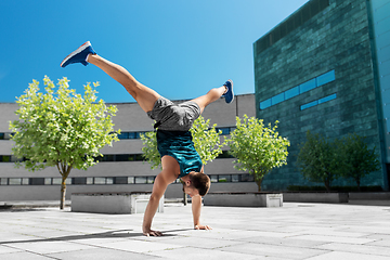 Image showing young man exercising and doing handstand outdoors